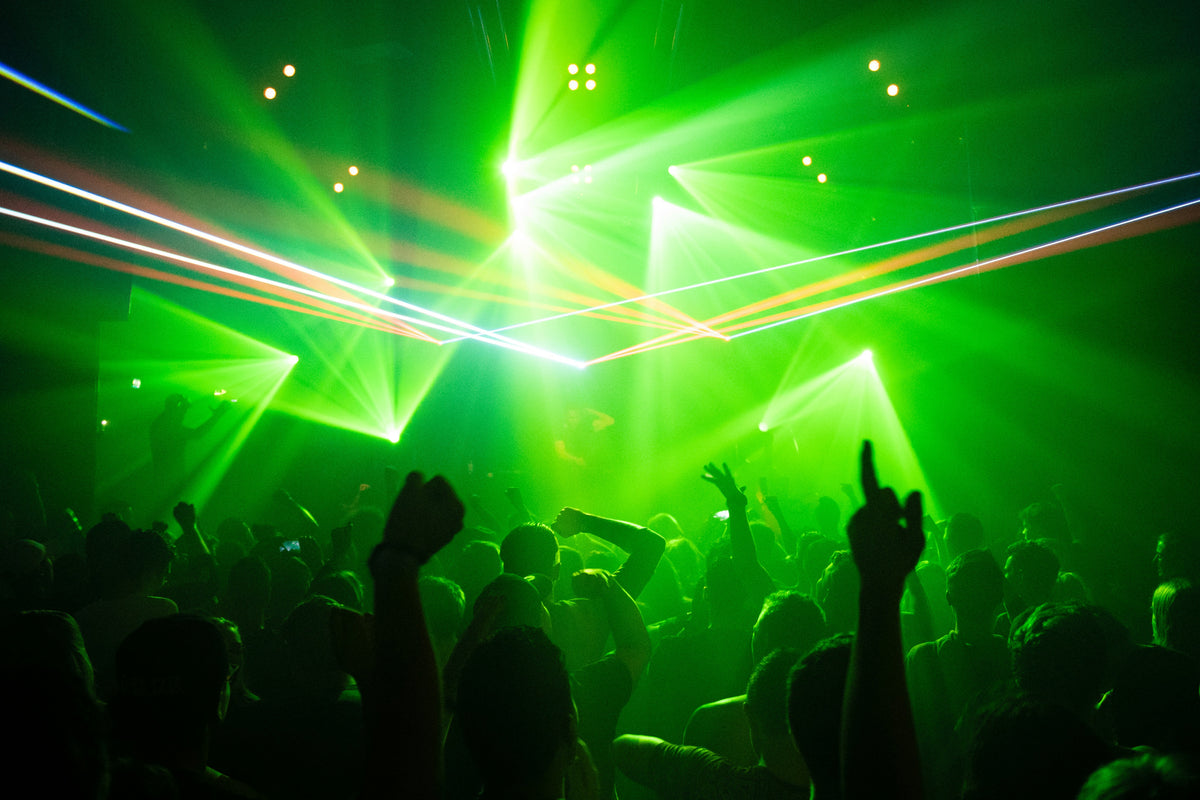 Tanzende Crowd im Techno-Club unter grünen Lasern