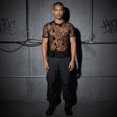 Ganzkörperansicht, Model im Shadow Bloom Meshshirt, Techno- und Rave-Mode, urbaner Hintergrund.